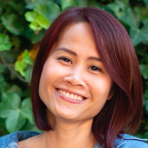 Chui Chui smiling in front of a leafy backdrop.