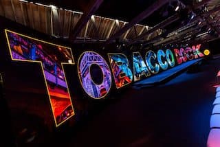 Glowing multicoloured three-dimensional letters inside the building spell out the words Tobacco Dock.